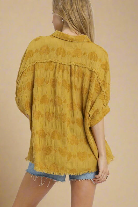 Yellow patterned blouse worn by a person on a beige background