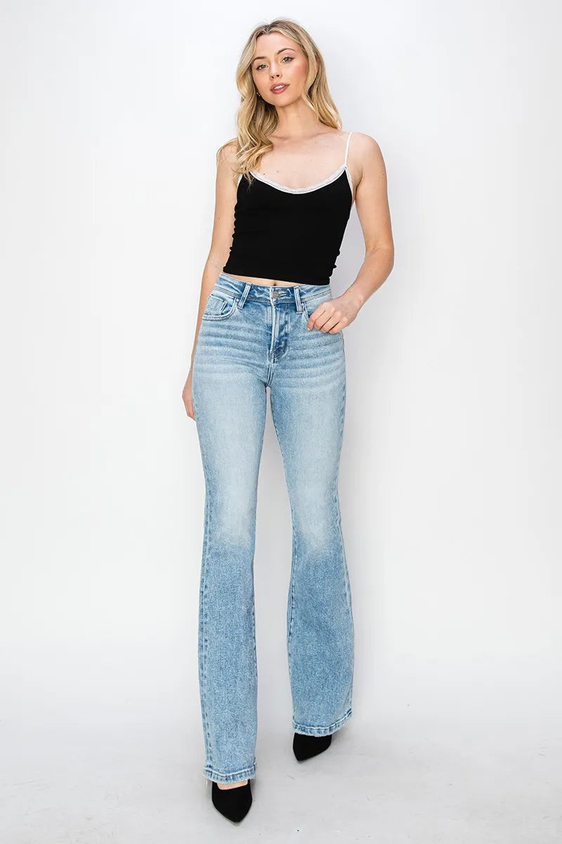 Woman wearing light blue flared jeans and a black top on a white background