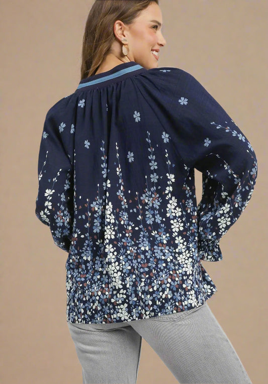 Woman wearing a navy floral blouse with gray pants on a white background