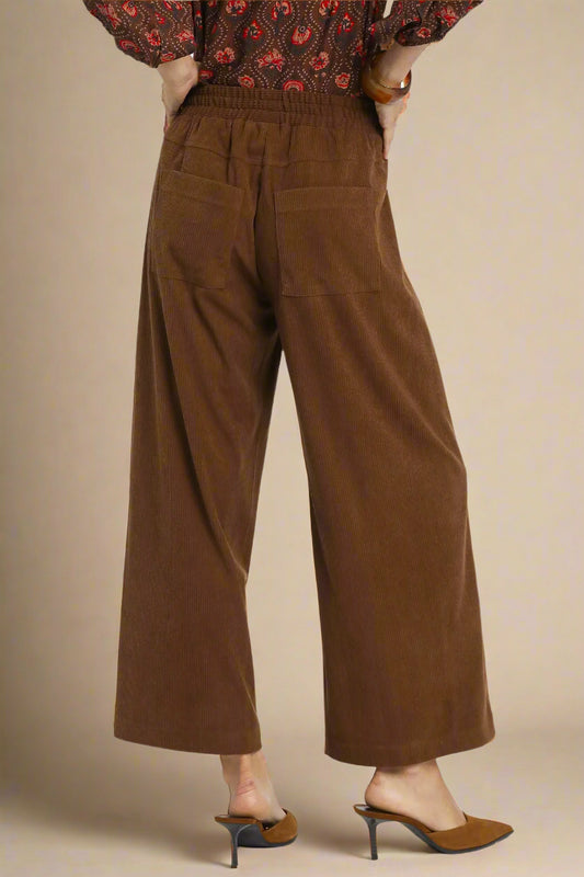 Brown wide-leg pants worn by a person on a beige background
