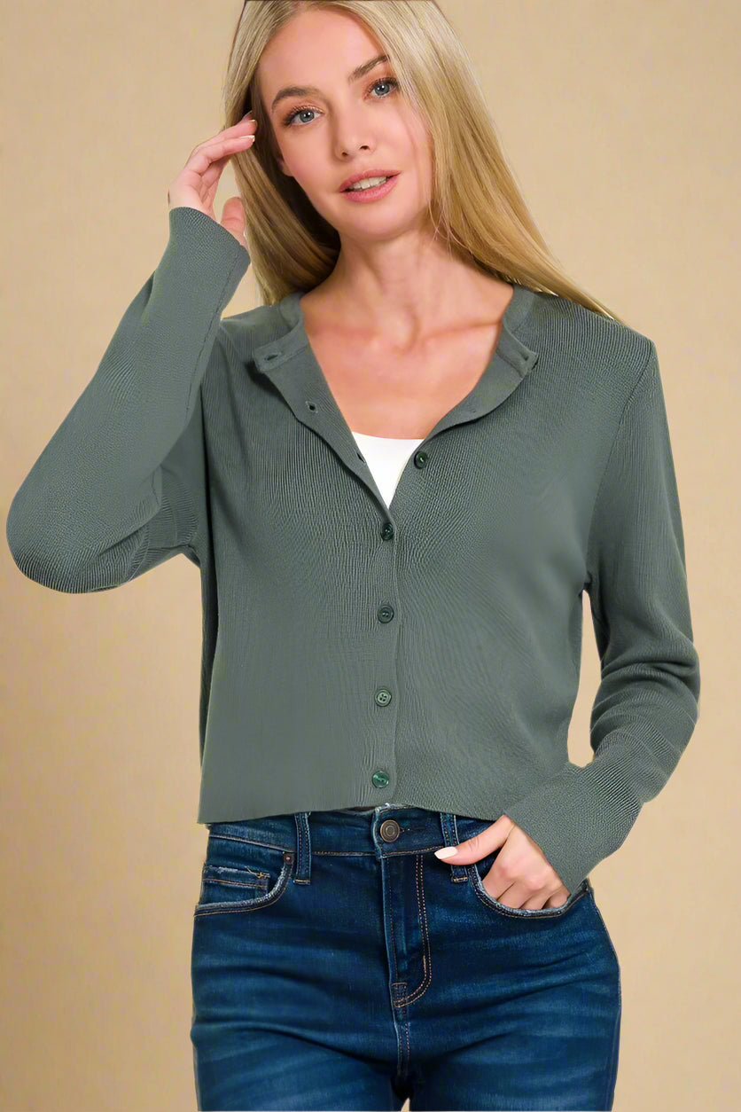 Woman wearing a green cardigan and blue jeans on a white background