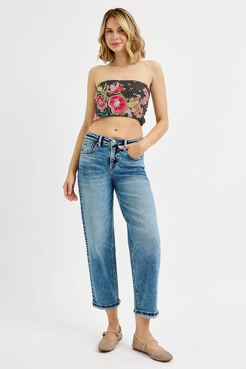 Woman wearing a floral bandeau top and blue jeans on a white background