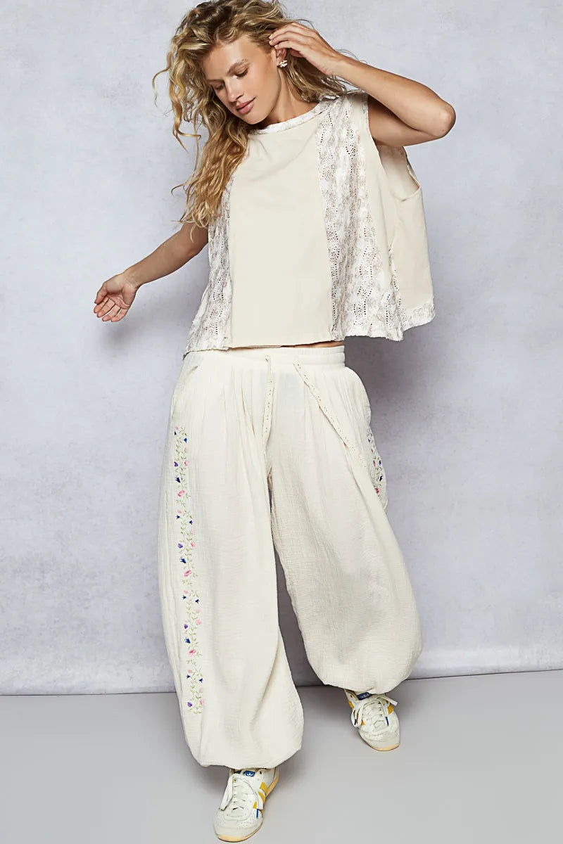 Woman wearing a white outfit with lace details against a light gray background