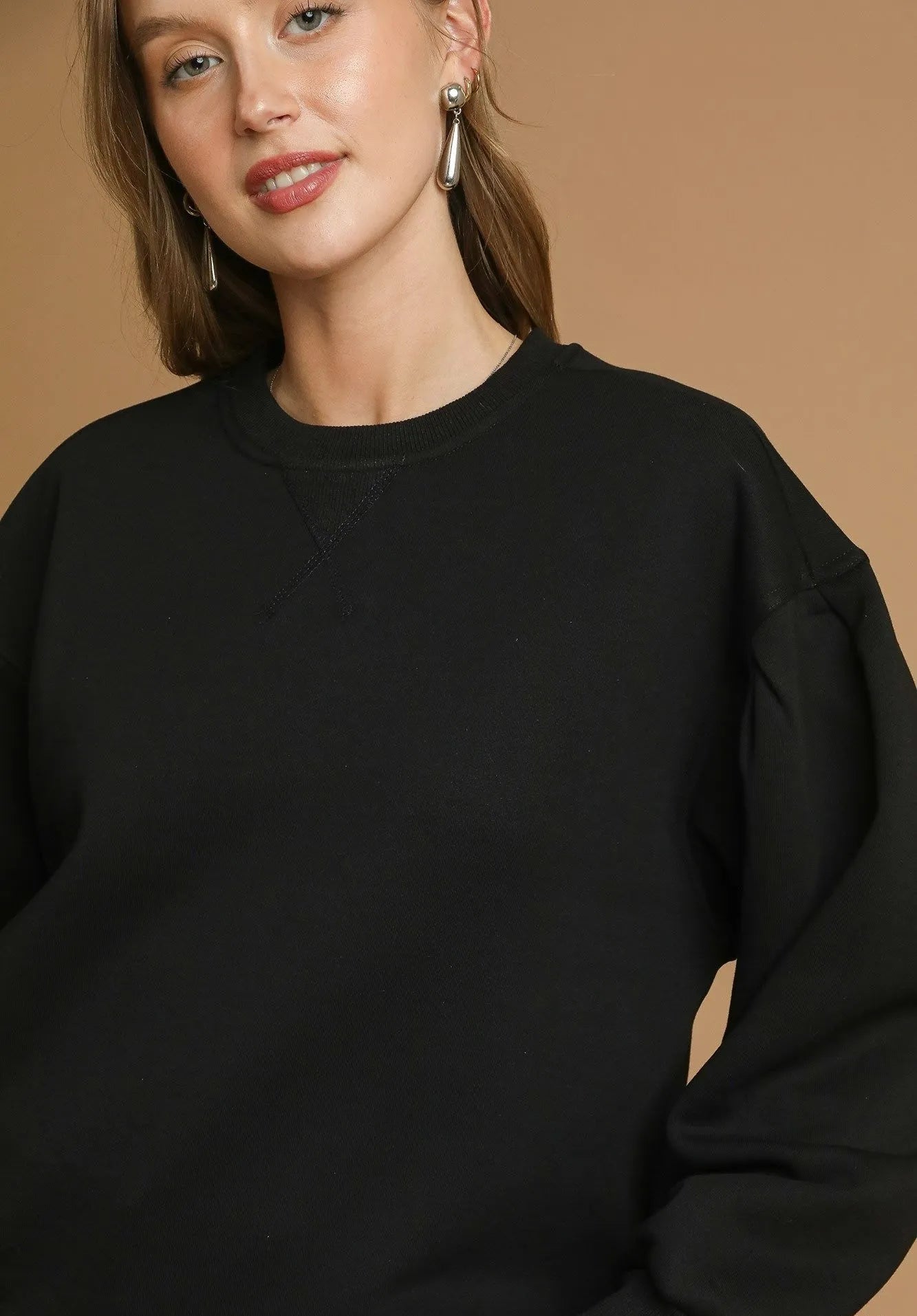 Woman wearing a black sweatshirt against a beige background