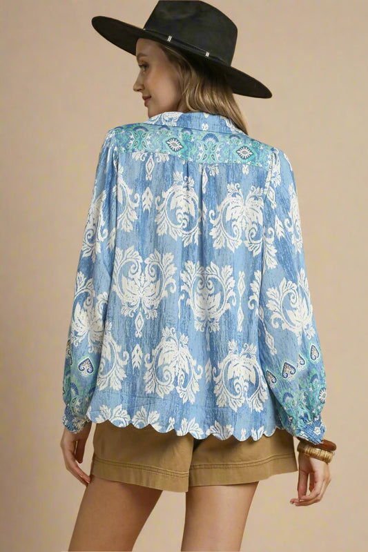 Woman wearing a blue patterned shirt and black hat on a beige background