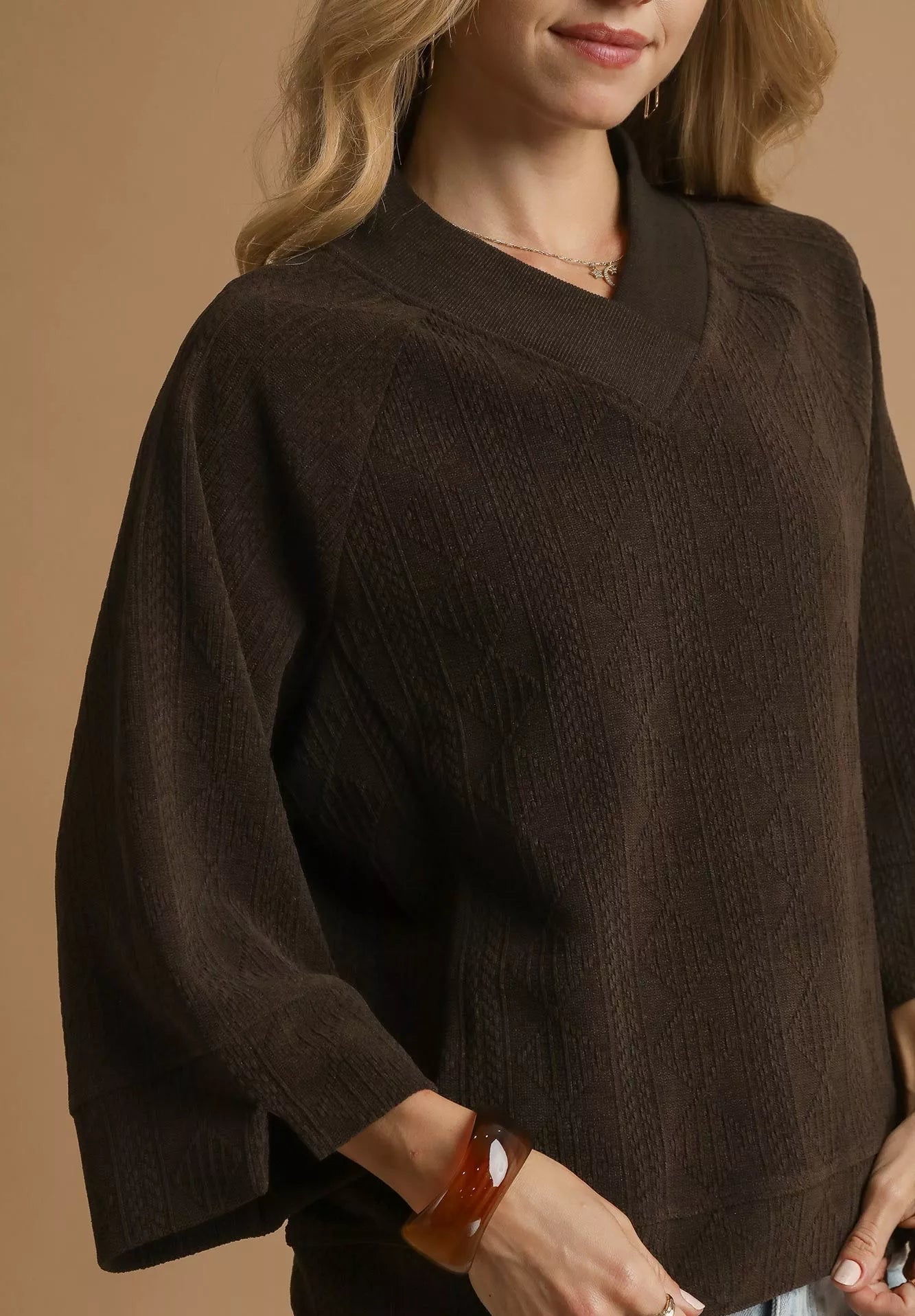 Brown sweater worn by a person on a beige background