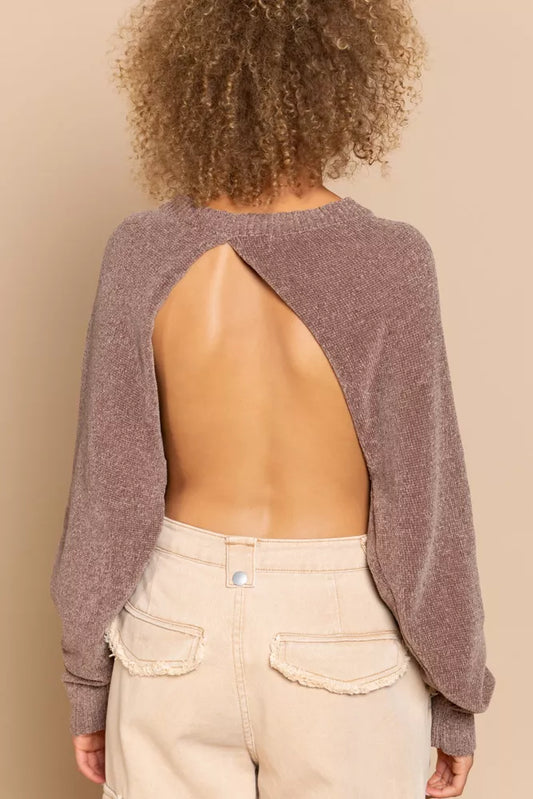 Person wearing a open-back sweater and beige pants on a beige background