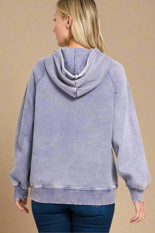 Person wearing a washed periwinkle hoodie on a beige background