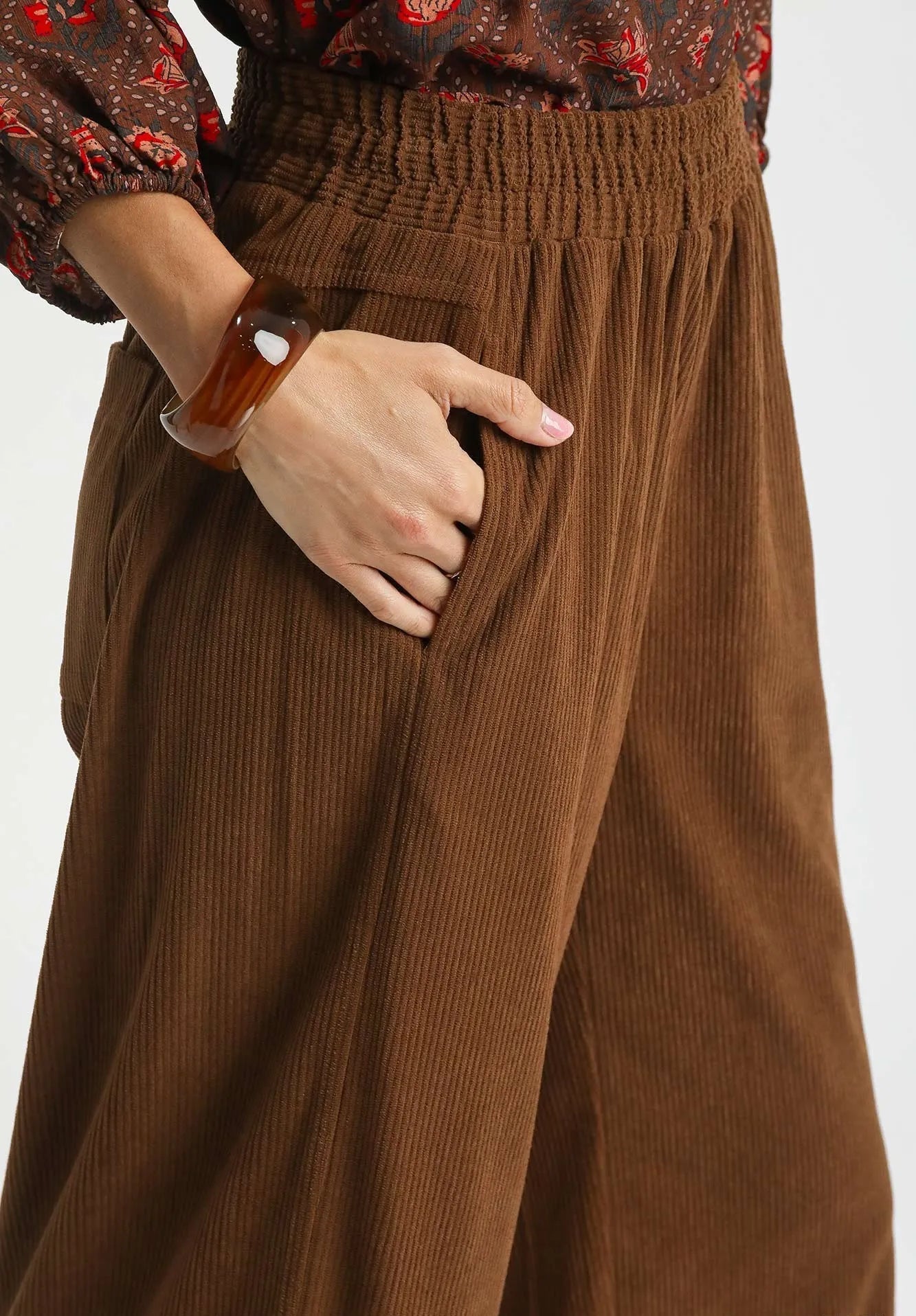 Brown corduroy pants worn by a person on a white background