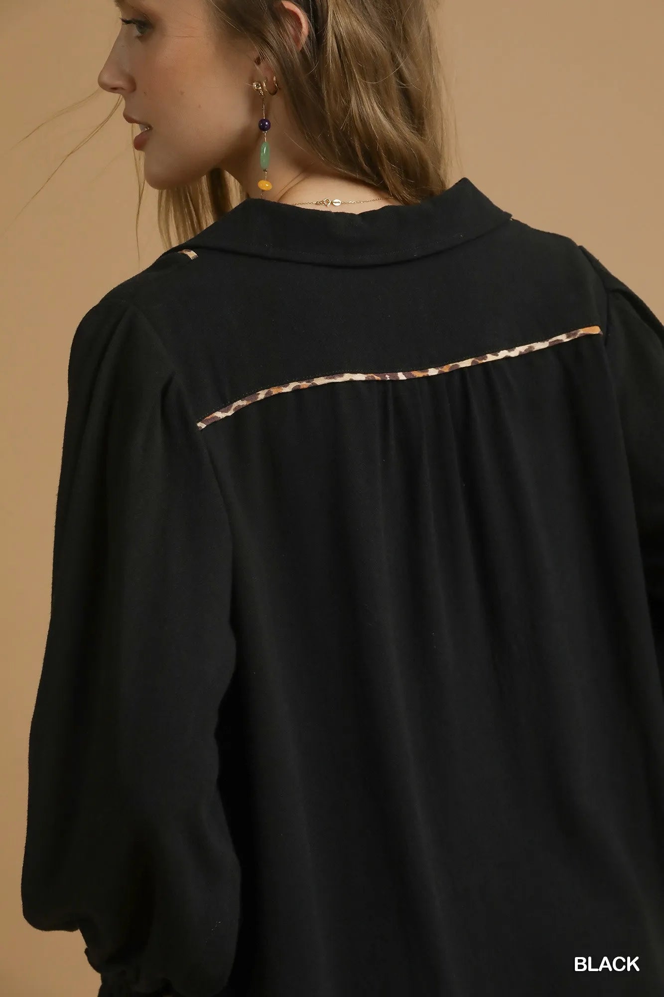 Black garment with decorative trim on a beige background