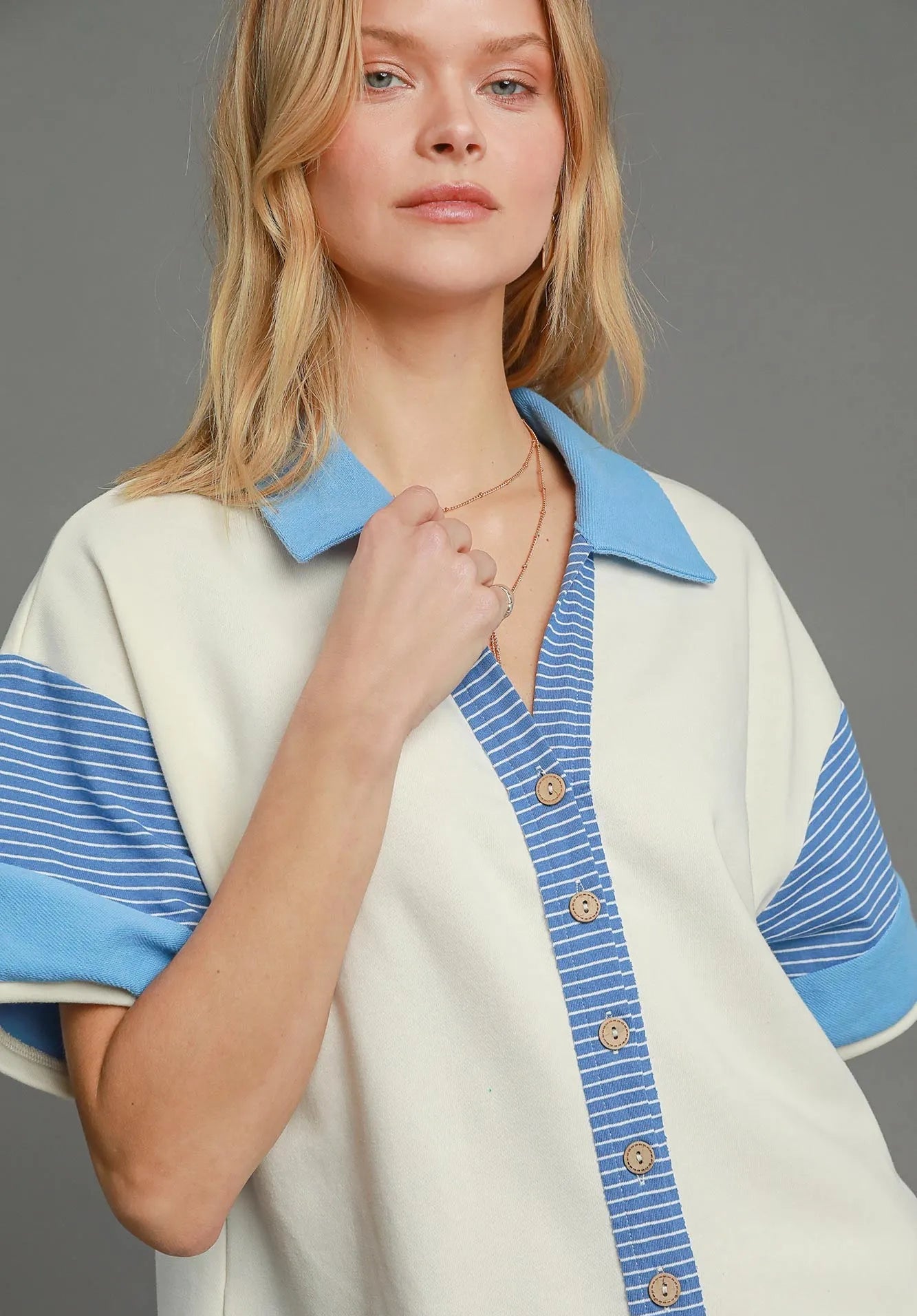 Woman wearing a cream and blue outfit with a gray background