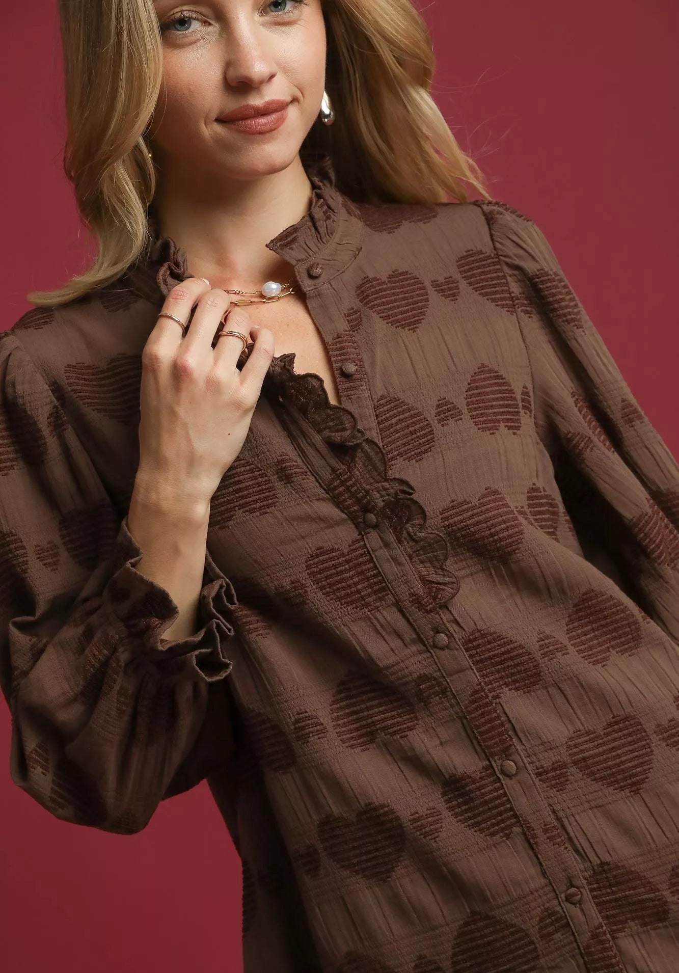 Woman wearing a brown patterned blouse against a red background