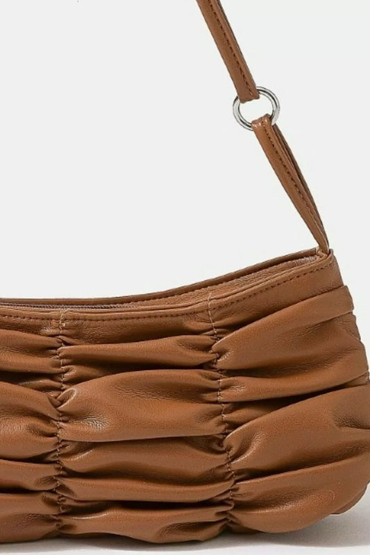 Brown leather handbag with a textured surface and visible stitching on a light gray background.