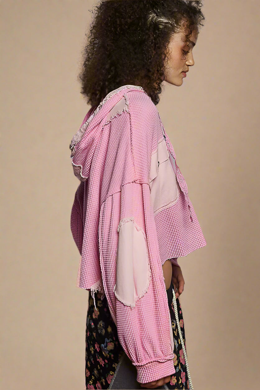 Person wearing a pink textured coat against a beige background