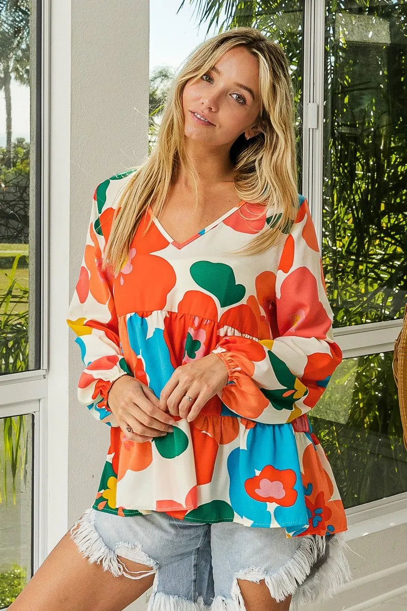 Woman wearing a colorful floral blouse with a blurred outdoor background