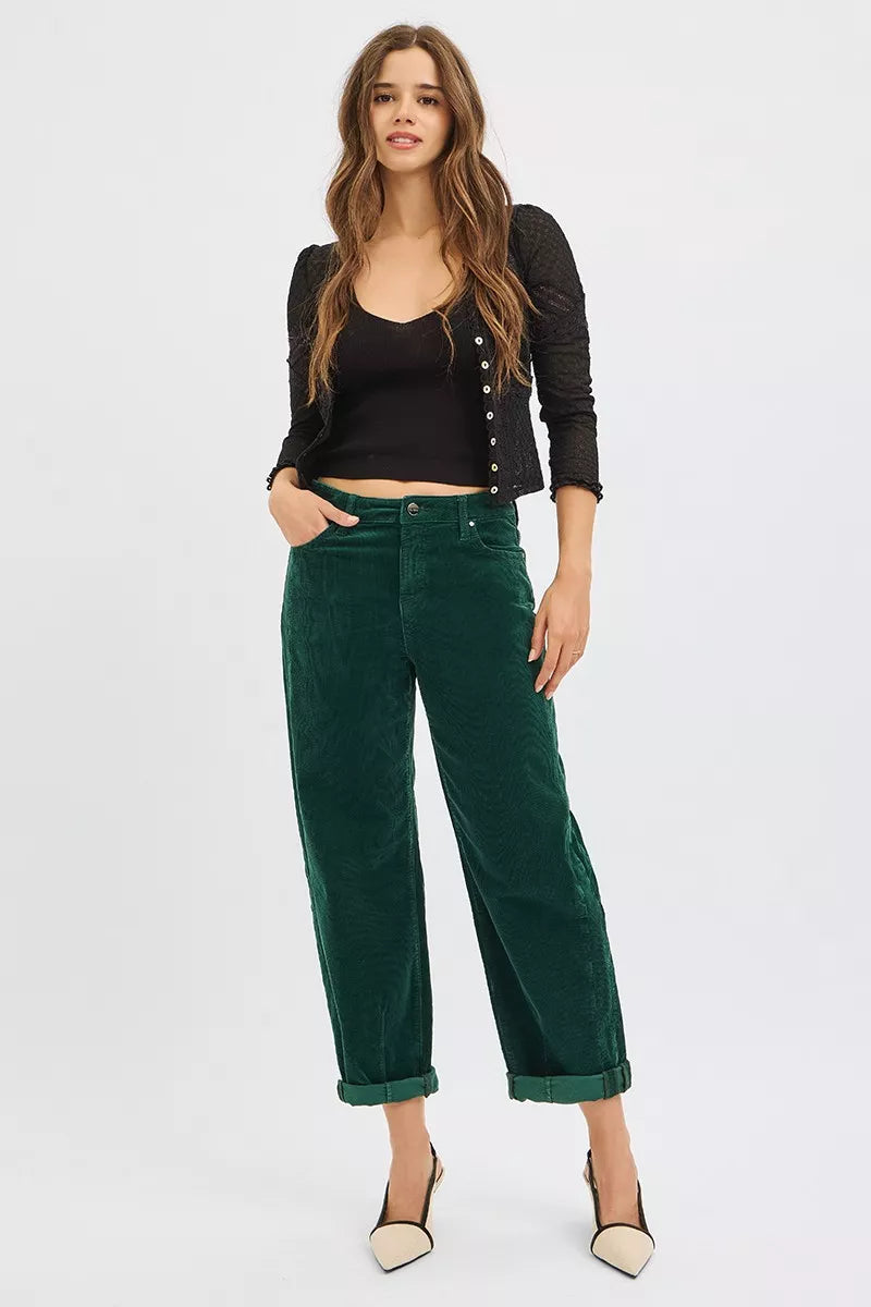Woman wearing a black cardigan and green pants on a white background