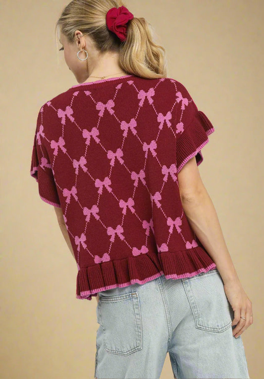 Woman wearing a burgundy sweater with pink bow pattern on a beige background