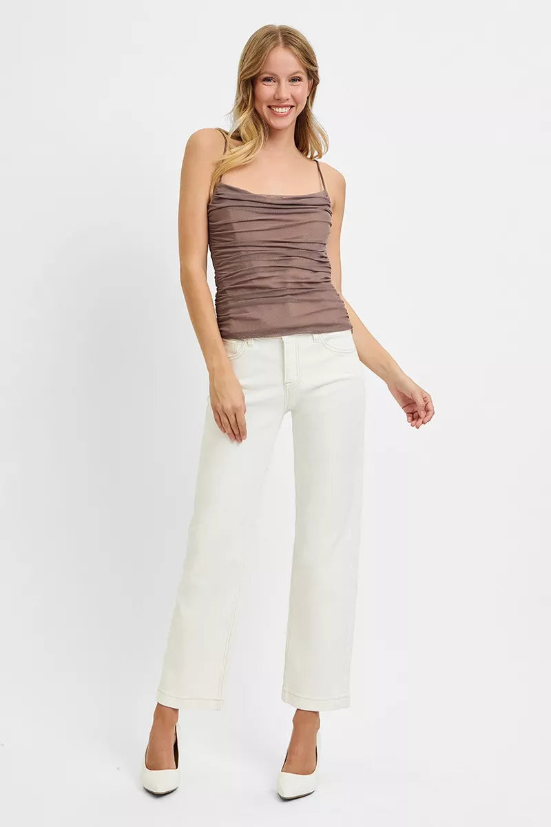 Woman wearing a brown tank top and white pants on a white background