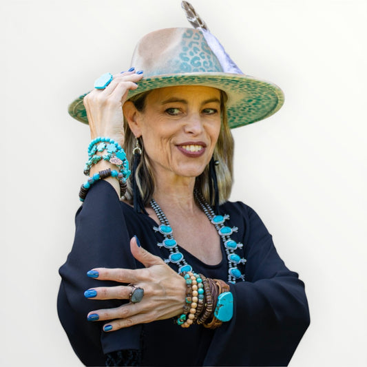 Woman wearing a stylish hat and colorful jewelry against a white background