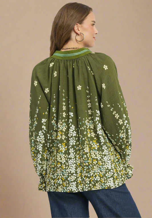 Woman wearing a green floral blouse with long sleeves on a beige background