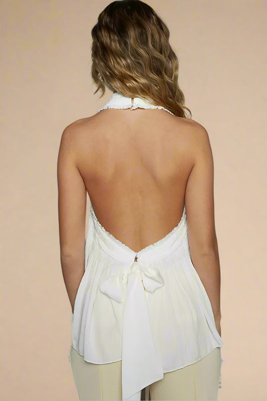 Woman wearing a white halter neck top with a plain background