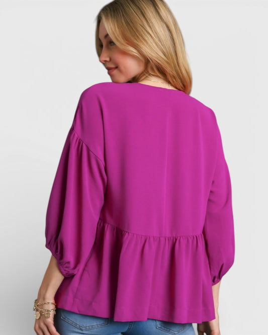 Woman wearing a bright pink blouse with puffed sleeves on a white background