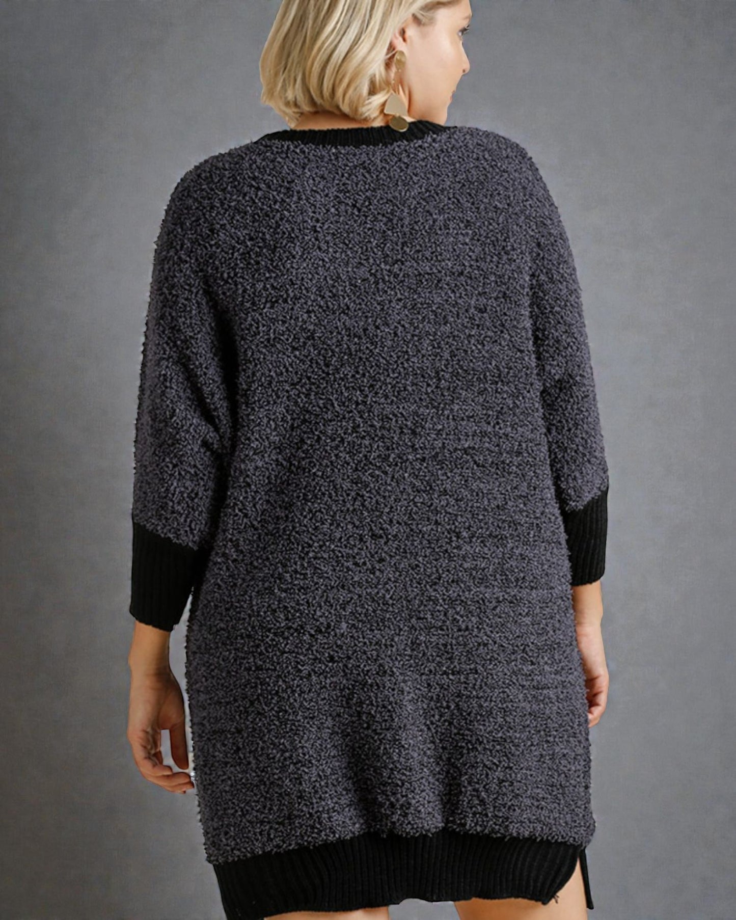 Person wearing a textured gray cardigan against a gray background