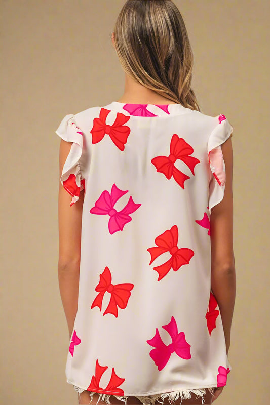 Woman wearing a sleeveless top with red and pink bow patterns on a white background