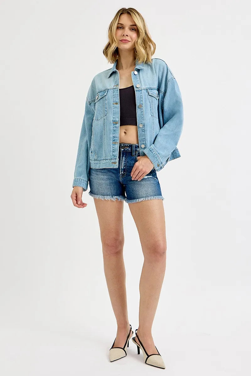 Woman wearing a light blue denim jacket and shorts on a white background
