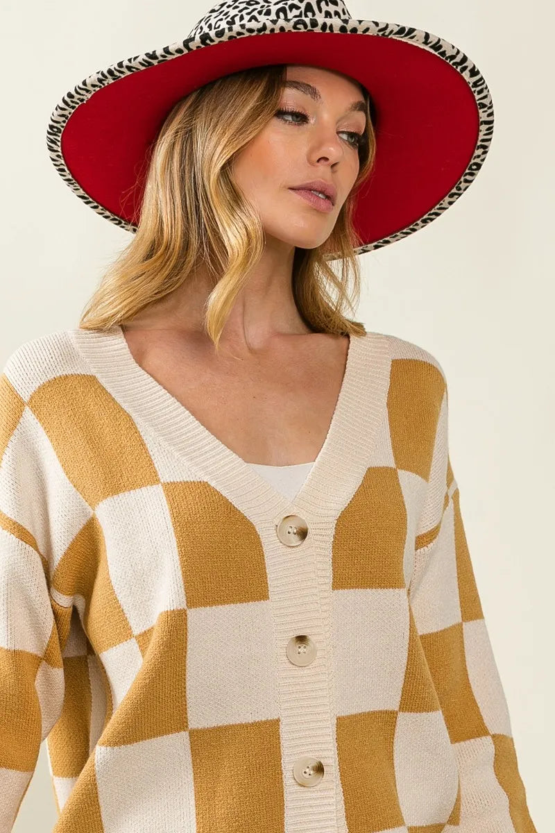 Woman wearing a checkered cardigan and red hat with black patterns on a beige background