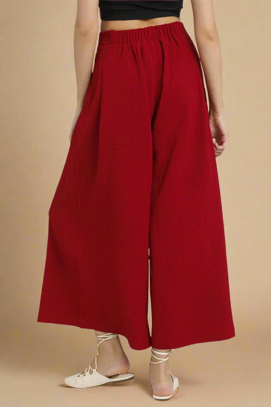 Red wide-leg pants worn by a person on a beige background