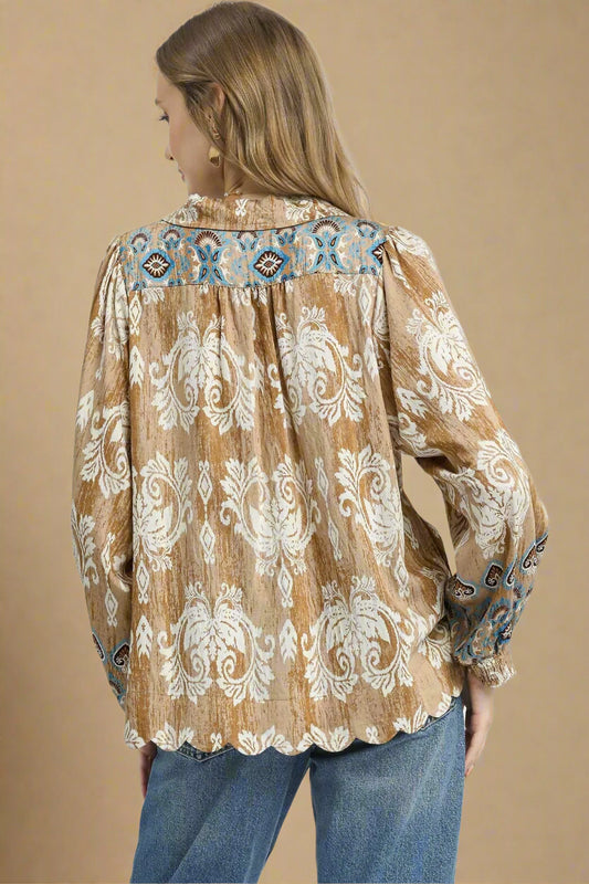 Woman wearing a patterned blouse with long sleeves on a beige background