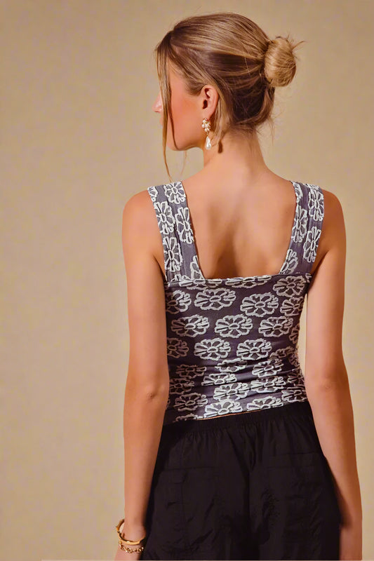 Woman wearing a sleeveless top with floral pattern on a beige background