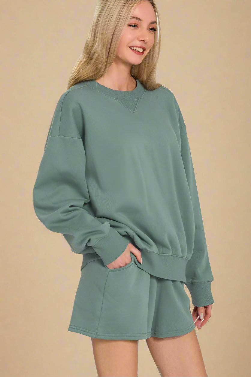 Woman wearing a green sweatshirt and shorts set on a white background