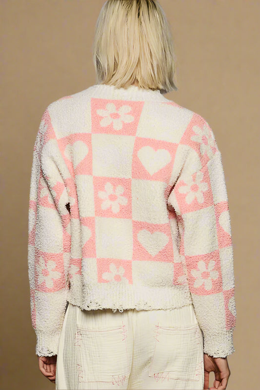 Person wearing a checkered cardigan with pink and white patterns on a plain background
