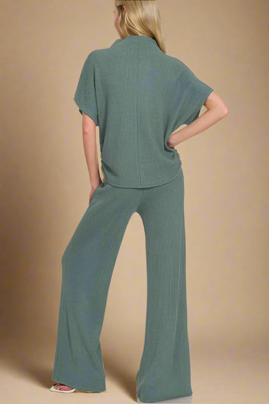 Woman wearing a green outfit with wide-leg pants on a beige background