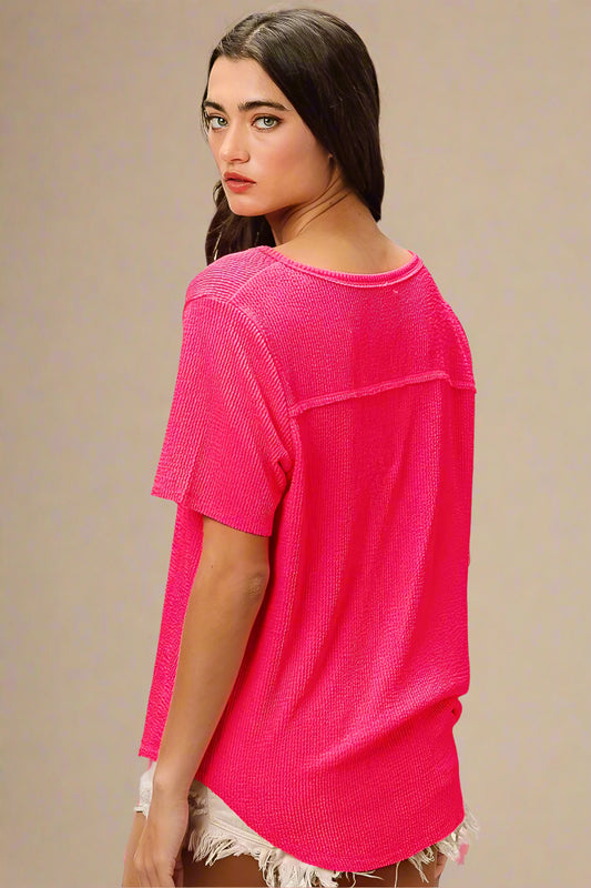 Woman wearing a bright pink textured top against a plain background