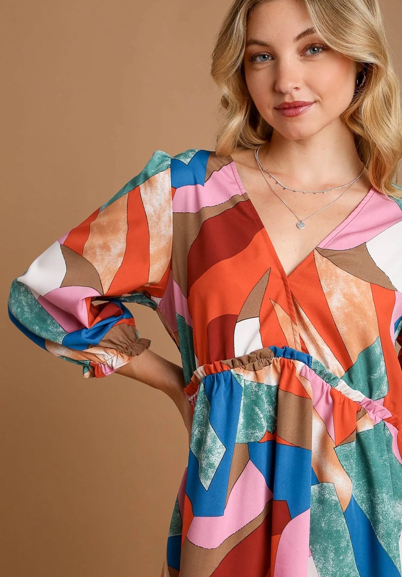 Woman wearing a colorful patterned dress against a brown background