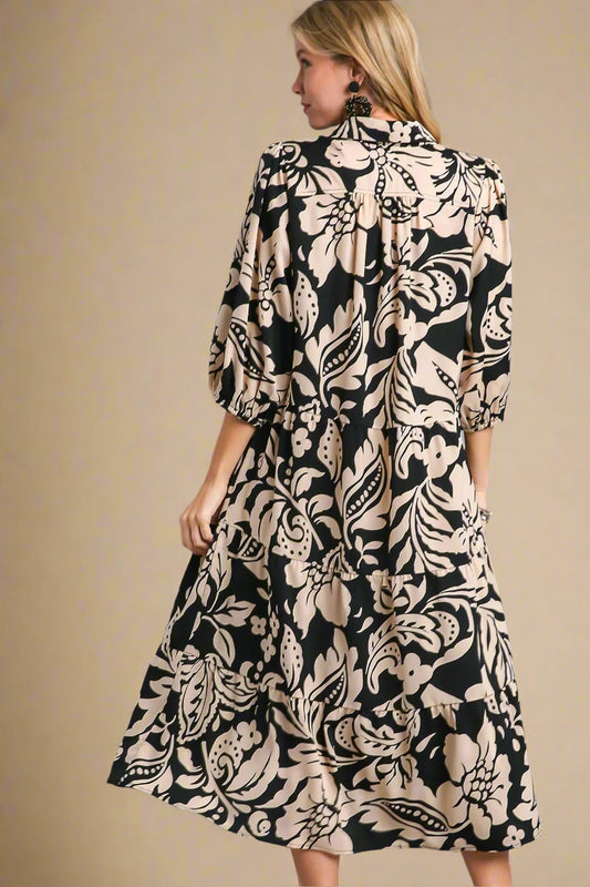 Woman wearing a black and beige patterned dress on a beige background