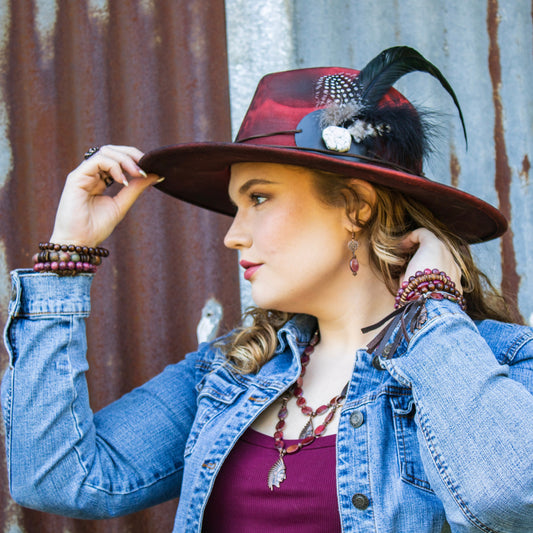 Woman wearing a stylish hat with feathers against a rustic metal background
