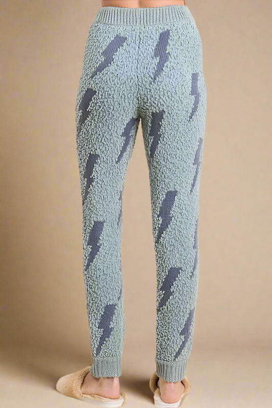 Light blue knitted pants with dark blue lightning bolt pattern on a beige background