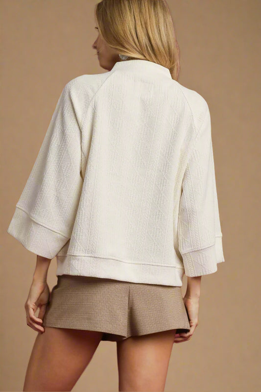 Woman wearing a white textured jacket and beige skirt on a red background