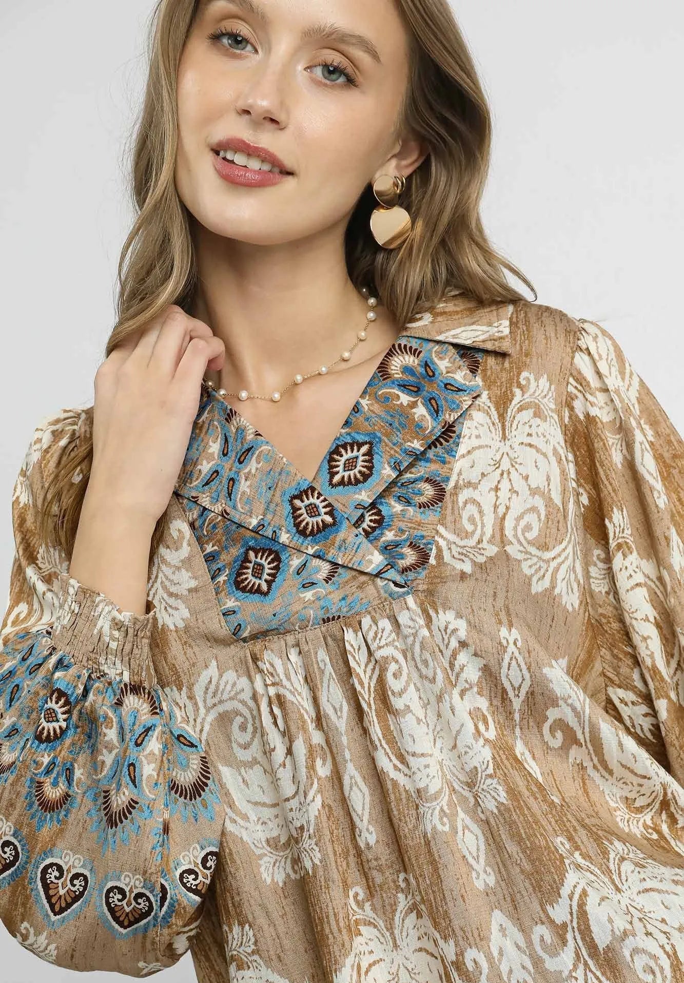 Woman wearing a patterned blouse with a neutral background