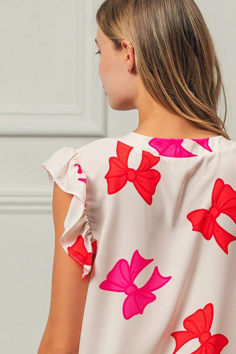 Woman wearing a dress with red and pink bow patterns on a plain background