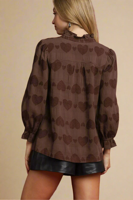 Woman wearing a brown blouse with heart patterns on a red background