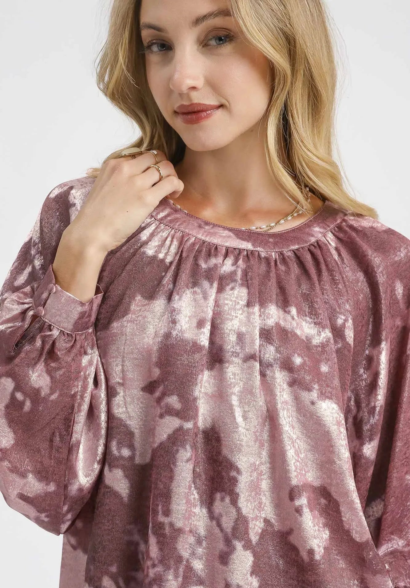Woman wearing a pink tie-dye blouse with a plain background