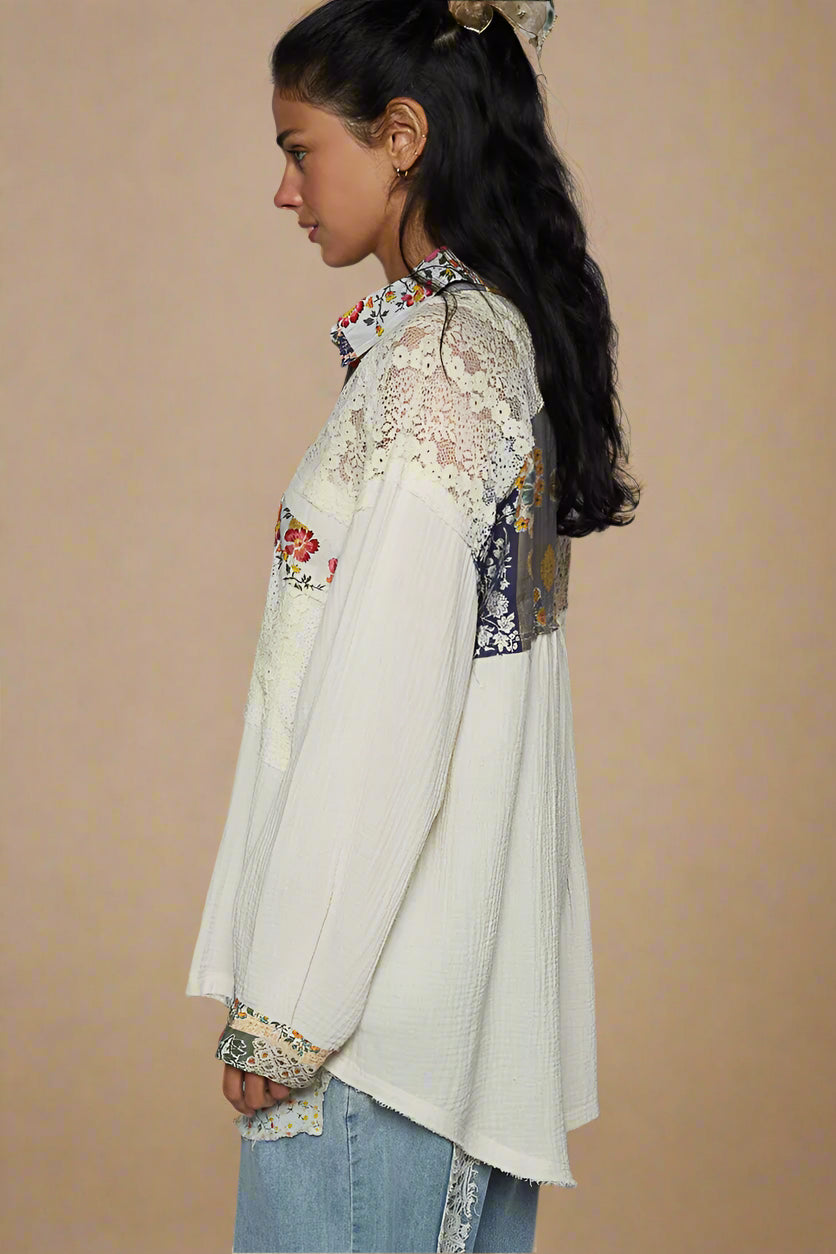 Woman wearing a white embroidered blouse with colorful patterns on a plain background