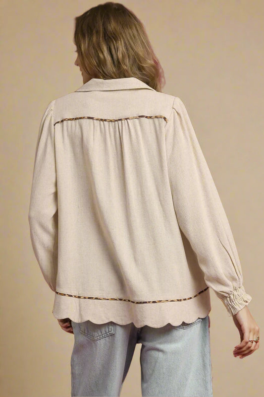 Person wearing a beige blouse with scalloped edges on a beige background