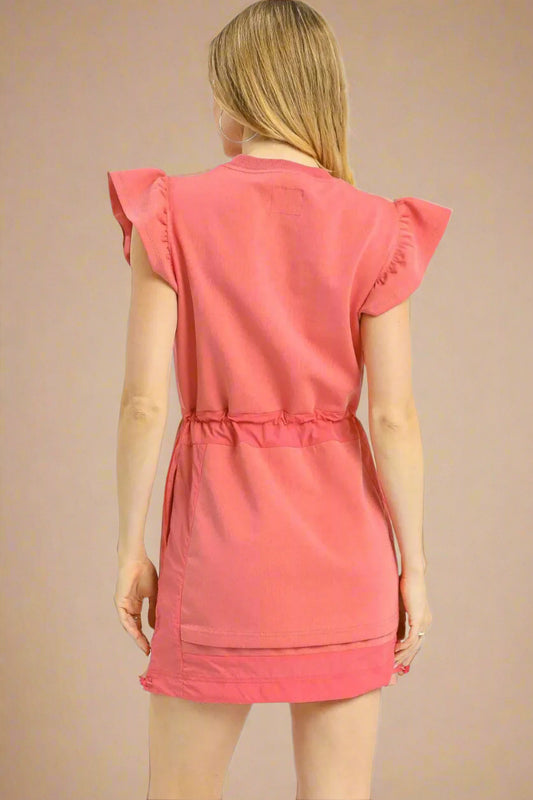 Woman wearing a pink dress with ruffled sleeves on a white background