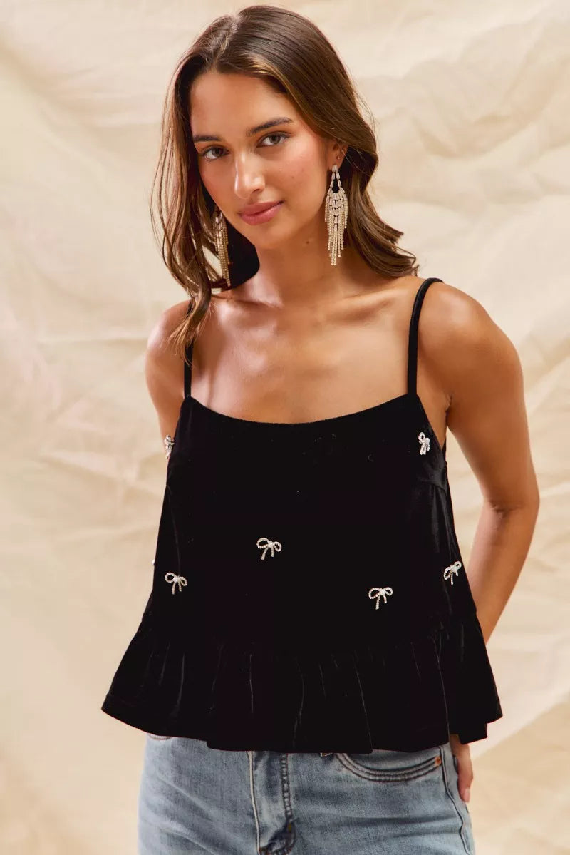 Woman wearing a black top with white embellishments against a beige background